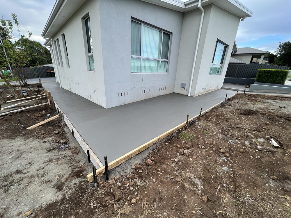 Freshly poured concrete patio beside a home